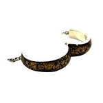A silver cuff bracelet featuring a textured, crackled gold and black pattern on the outer surface, shown against a plain white background.