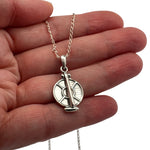Small silver tortillero charm pendant held in hand to show actual size