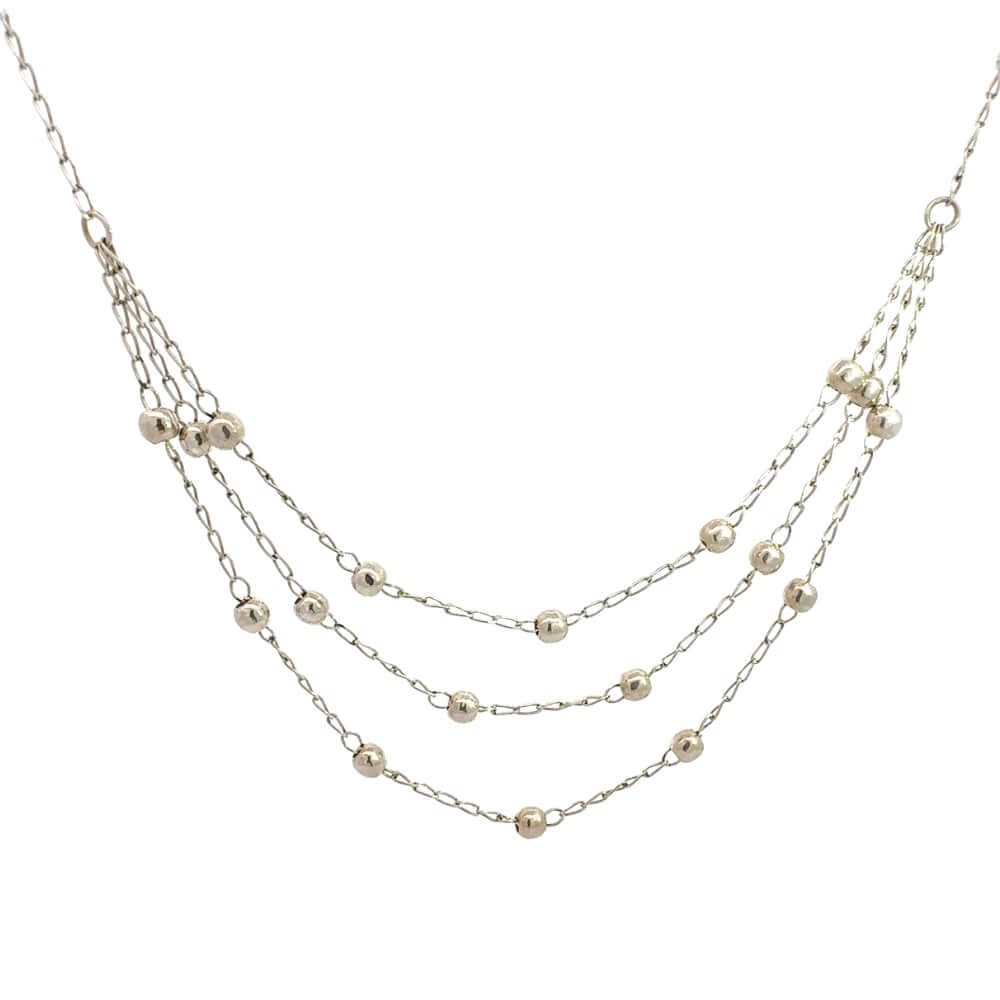 Close up of a delicate 24-inch three-strand sterling silver bead necklace