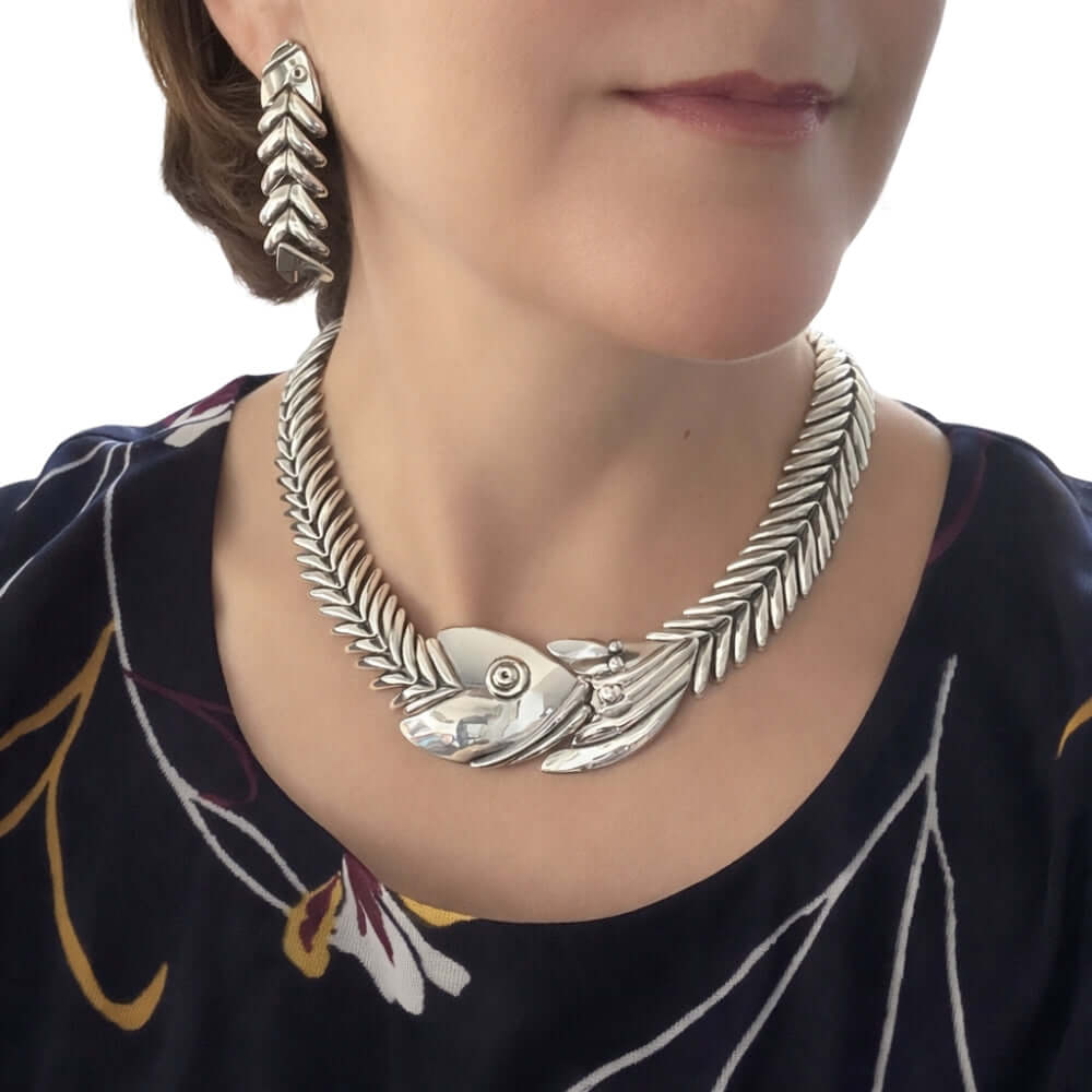 Close-up of a woman wearing the articulated silver fishbone statement necklace with matching drop earrings.