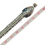 The articulated silver fishbone necklace laid out next to a measuring tape, showing the full length reaching past 19 inches (50 cm) for a comfortable, statement-sized fit.