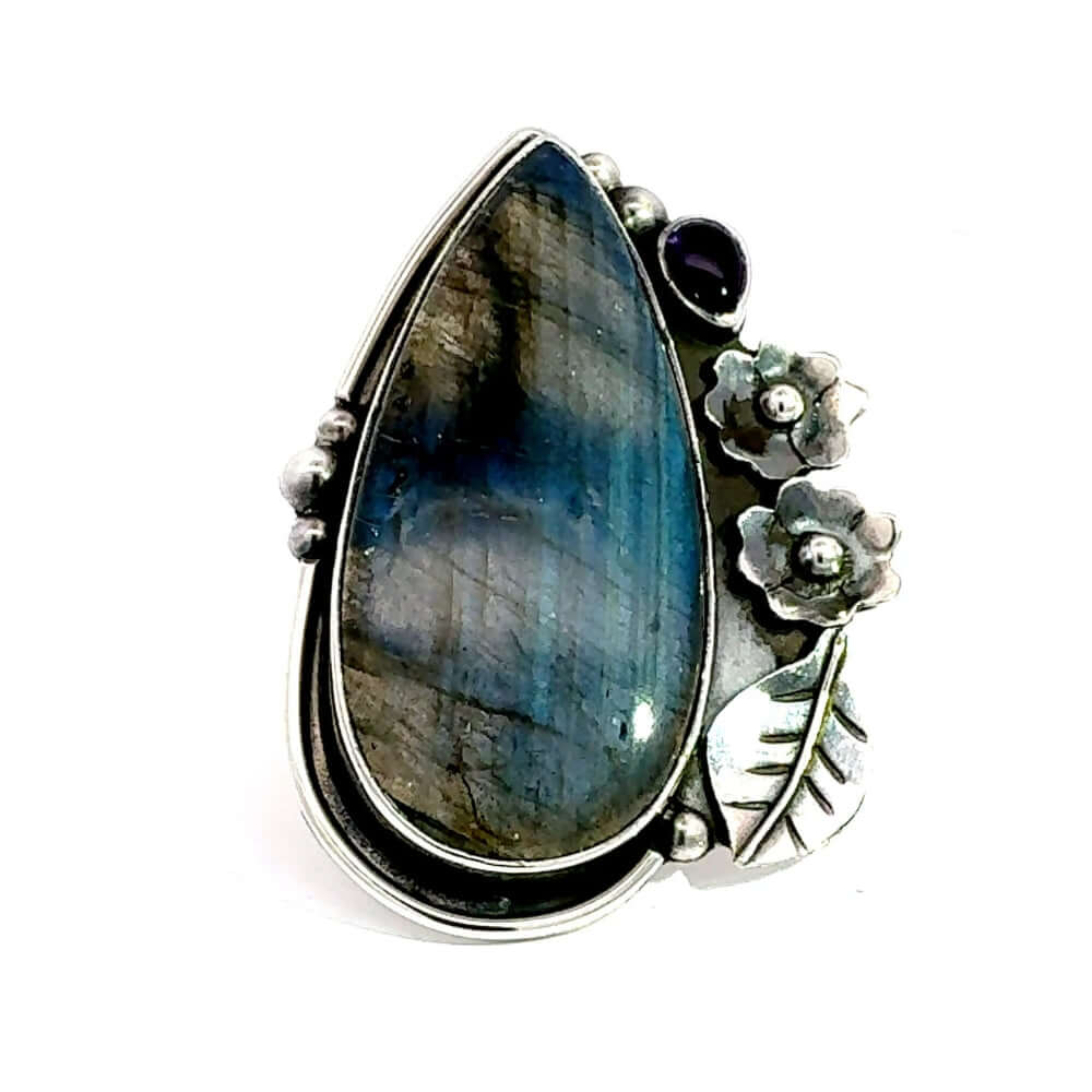 Front view of a handmade 950 silver long ring featuring a teardrop labradorite, carved silver flowers, and an oval amethyst stone.