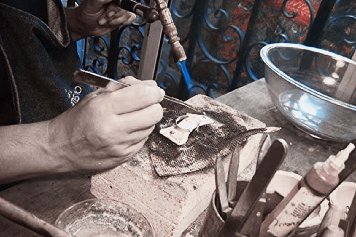 Close-up of a master silversmith in Taxco, Mexico, using a traditional blowtorch to handcraft silver jewelry, showcasing the heritage and authentic artisan techniques of the region.