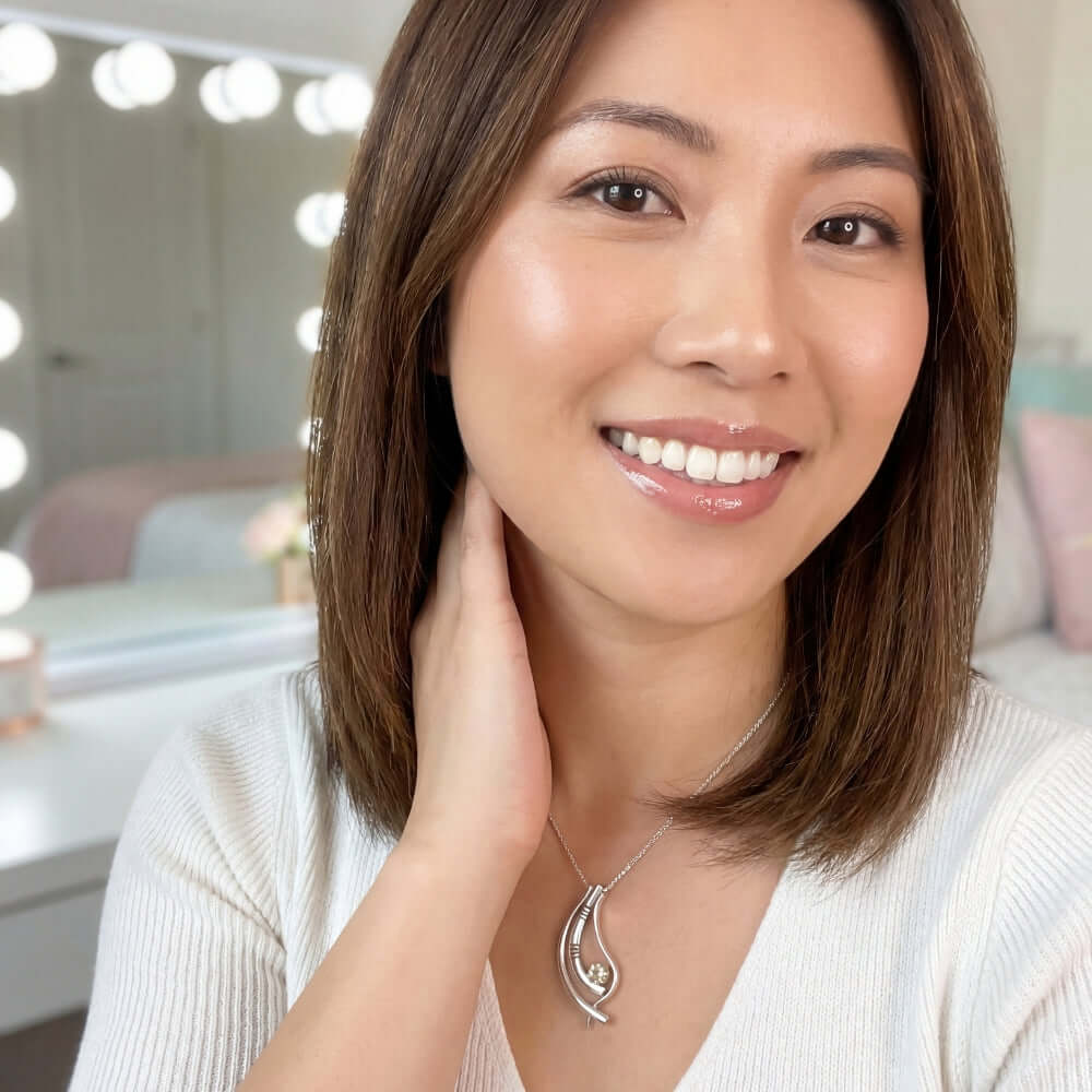 A woman smiling while wearing a hand-forged Mexican silver pendant with a golden citrine stone.