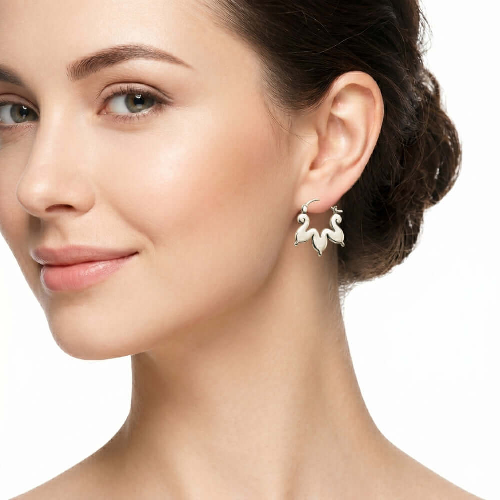 A woman wearing Stuart Alarcón's hand-forged silver cloud hoops inspired by Mexican codices.