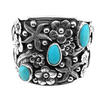 Front view of a wide handmade 925 sterling silver cuff bracelet featuring three blue turquoise stones nestled in detailed silver floral carvings.