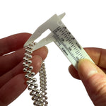 Caliper measuring the silver beads of the triple silver bracelet against a white background
