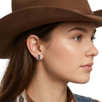 Side view of an artisan silver cowboy boot post earring worn with a western hat, illustrating its delicate scale.